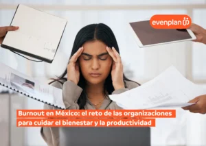 Burnout-en-Mexico - Evenplan Mujer con las manos en la cabeza rodeada de papeles, cuadernos y una tablet, transmitiendo estrés por carga de trabajo y burnout.